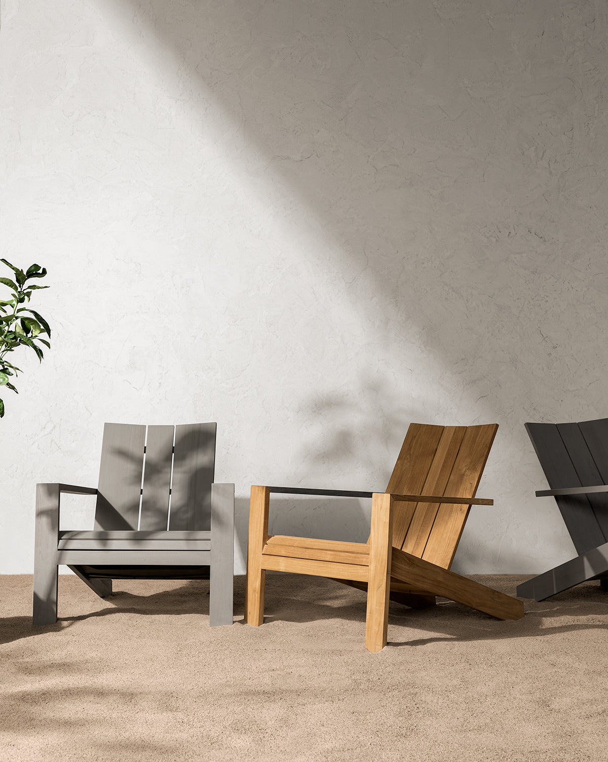 A Triby Gray Teak Outdoor Lounge Chair sits on a beige carpet against a textured light wall, with sunlight casting shadows and a green plant partially visible to the left, by Vendixs