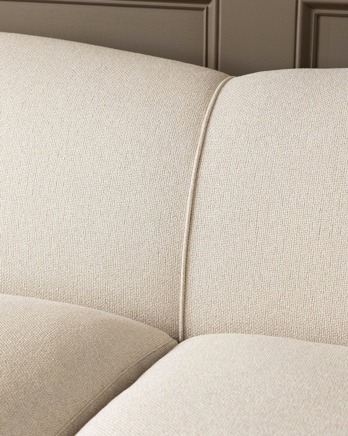 The Rowley Sofa 85 by Rowe Fine Furniture, Inc., showcasing beige fabric upholstery, visible stitching, and textured cushion details against a paneled wall. Customizable fabric options available. Vendixs