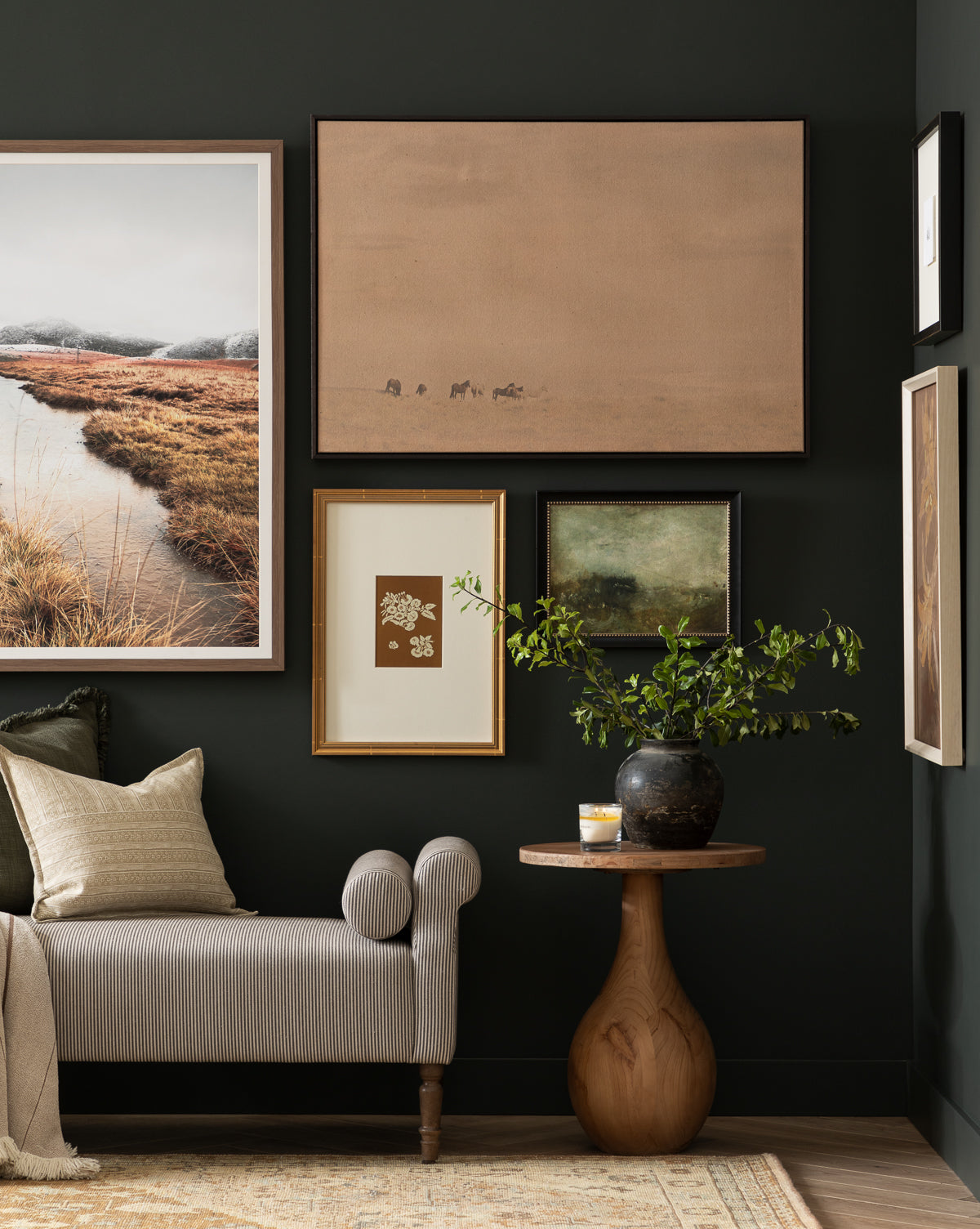 A cozy living space with a gray chaise lounge, beige pillow, round wooden side table, black vase with greenery, and the Smokey Pasture country landscape wall art framed on a dark green wall, by Vendixs