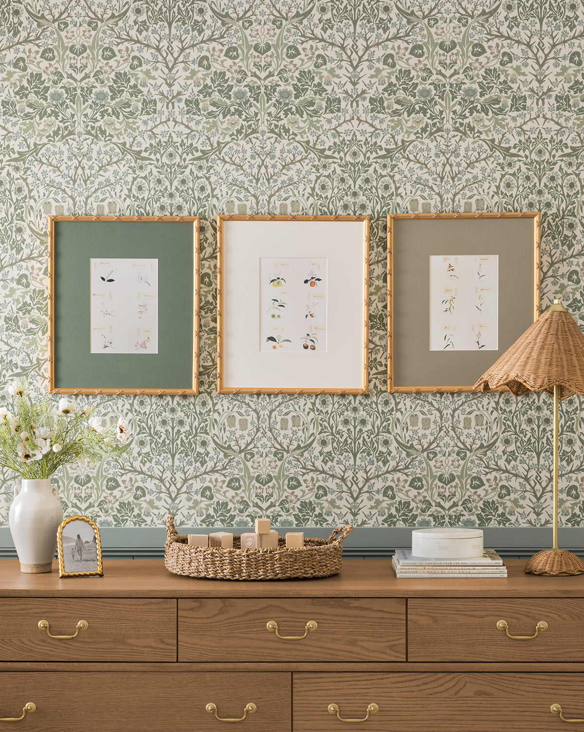 A wooden dresser holds decor under green floral wallpaper, where the Botanical Grid 1 giclee print in a gold frame adds style among other botanical wall art pieces, by Vendixs