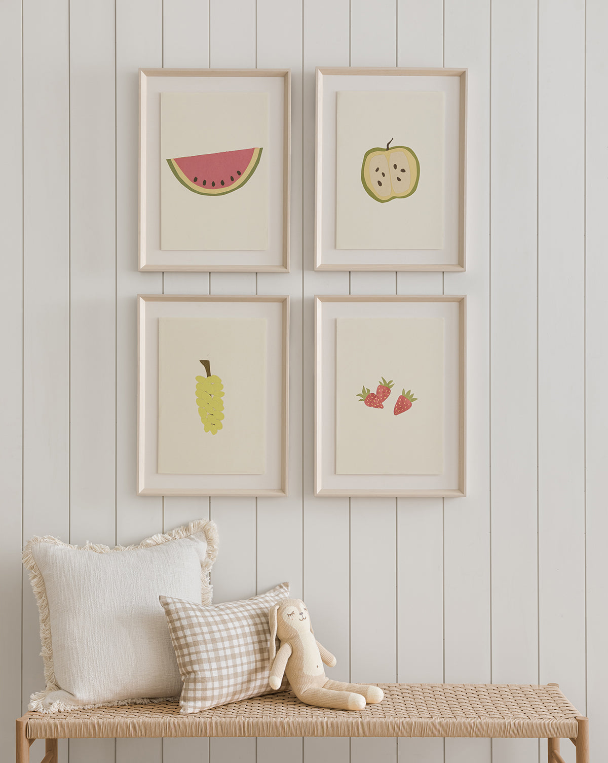 The framed Watermelon Collage hangs on a white paneled wall above a bench with neutral cushions and a stuffed bunny, creating a cheerful accent for any childrens room, by Vendixs