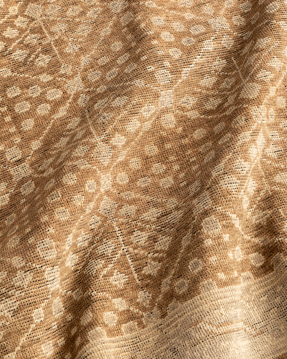 A close-up of the Windsor Hand-Knotted Wool Rug in beige and brown shows its intricate geometric and floral pattern, with subtle folds that highlight the rug's detailed texture and handcrafted design, by Vendixs
