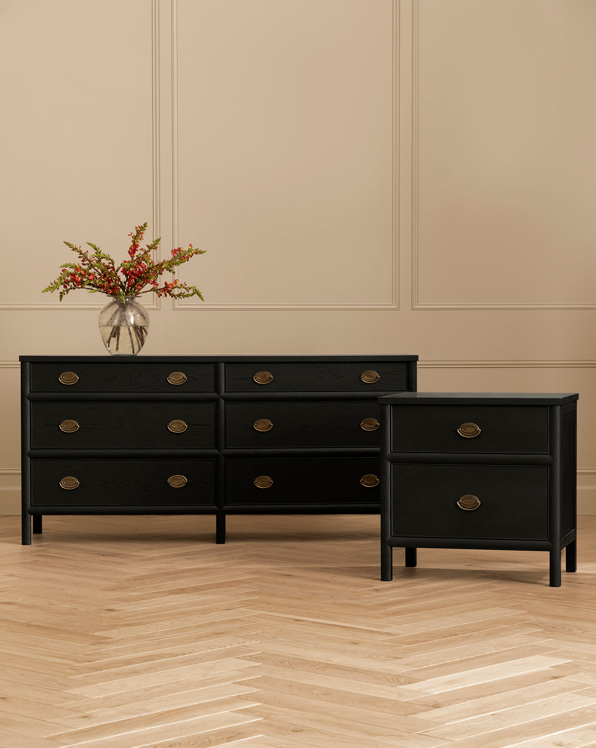 The Edward Dresser, finished in sleek black ash with six drawers and round brass handles, offers elegant bedroom storage. Pair it with the matching nightstand and top with a glass vase of red flowers for a vibrant accent by Vendixs