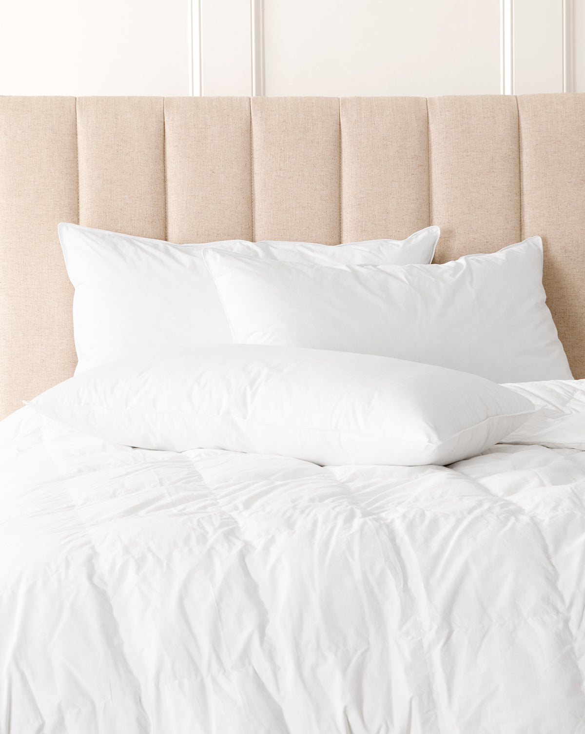 White bedding set on a bed with a beige headboard from Vendixs