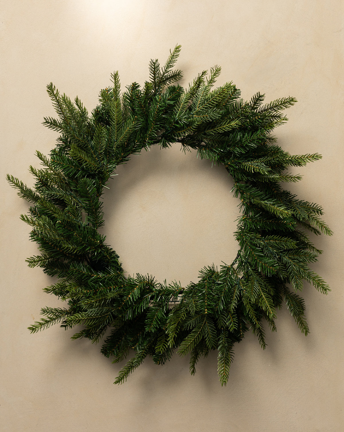 The 32" Grandis Pre-Lit Indoor/Outdoor Faux Wreath, featuring dense, natural-looking greenery, hangs beautifully on a light-colored wall—perfect for enhancing your holiday decor, by Vendixs