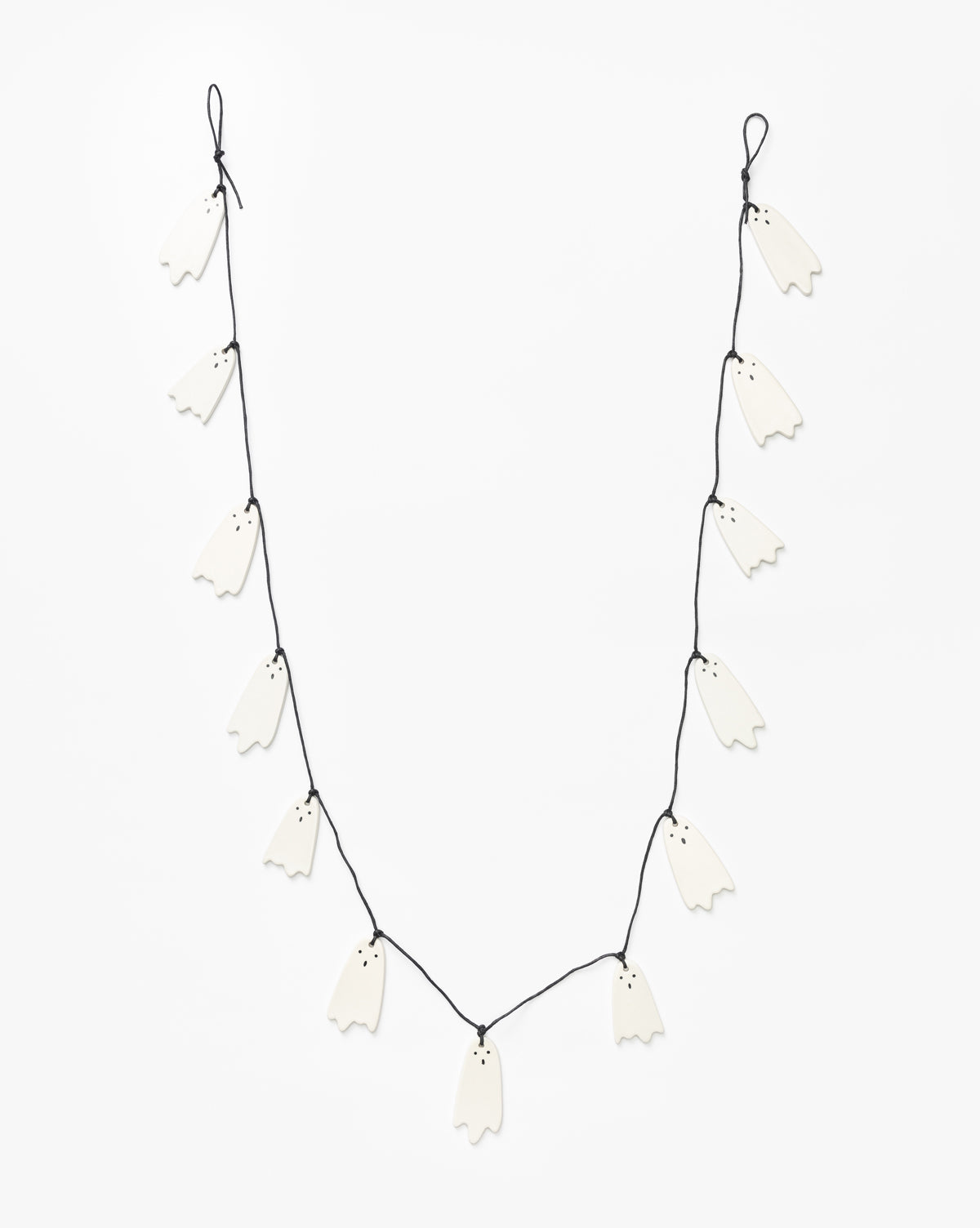 The 3 Ceramic Ghost Garland features small black-eyed ceramic ghosts evenly spaced on a black string, perfect for Halloween decor, by Vendixs