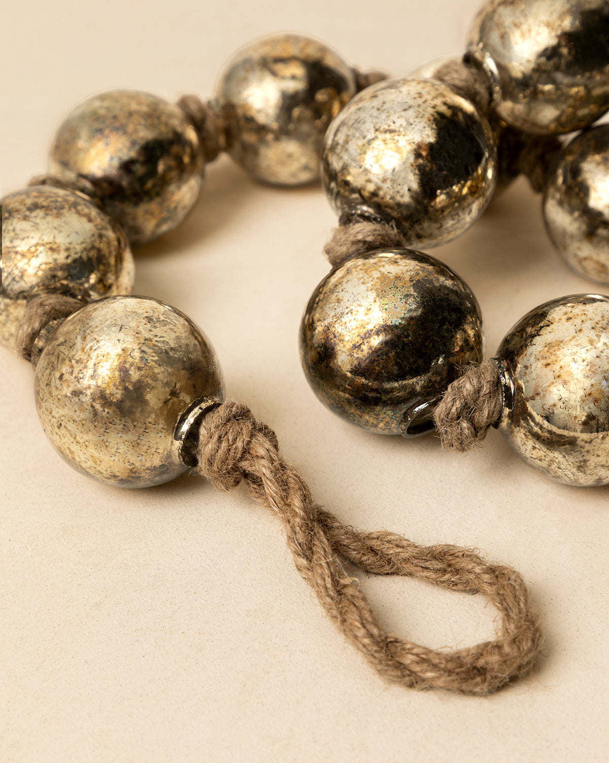 A close-up of the 4.4' Aged Silver Glass Garland, featuring large round silver beads on thick twine in a loop, displayed on a neutral background—ideal for vintage holiday decor, by Vendixs