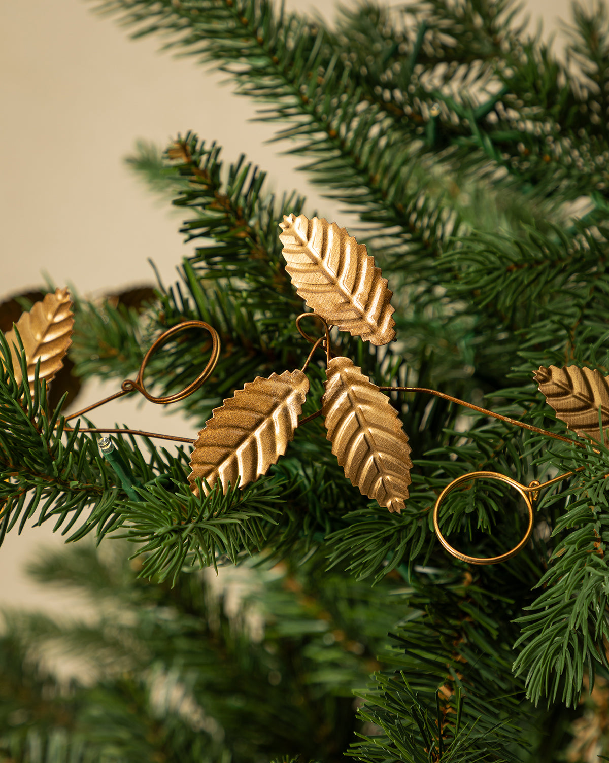The 6' Card Holder Garland features golden leaf-shaped ornaments hanging on green pine branches, adding a festive and elegant touch—ideal for highlighting vintage-inspired holiday decor, by Vendixs