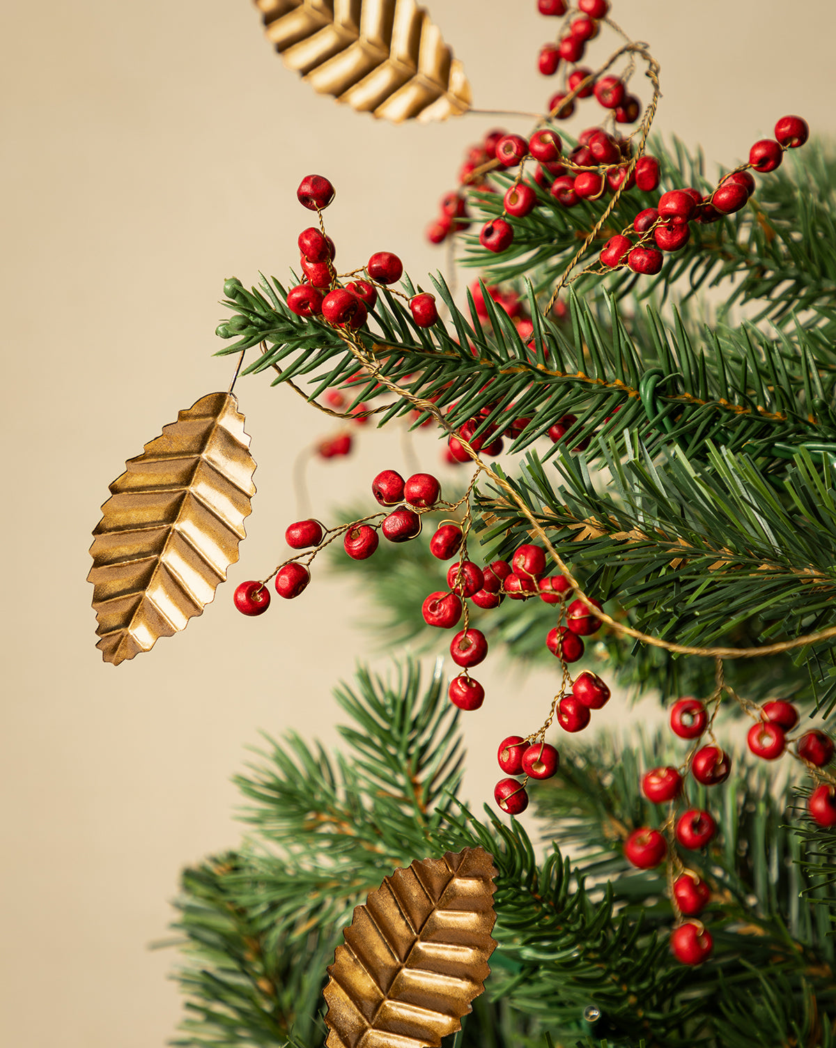 Close-up of the 6' Holly Berry Garland, featuring pine branches, red berries, and gold metallic leaves—perfect for festive holiday décor against a beige background, by Vendixs