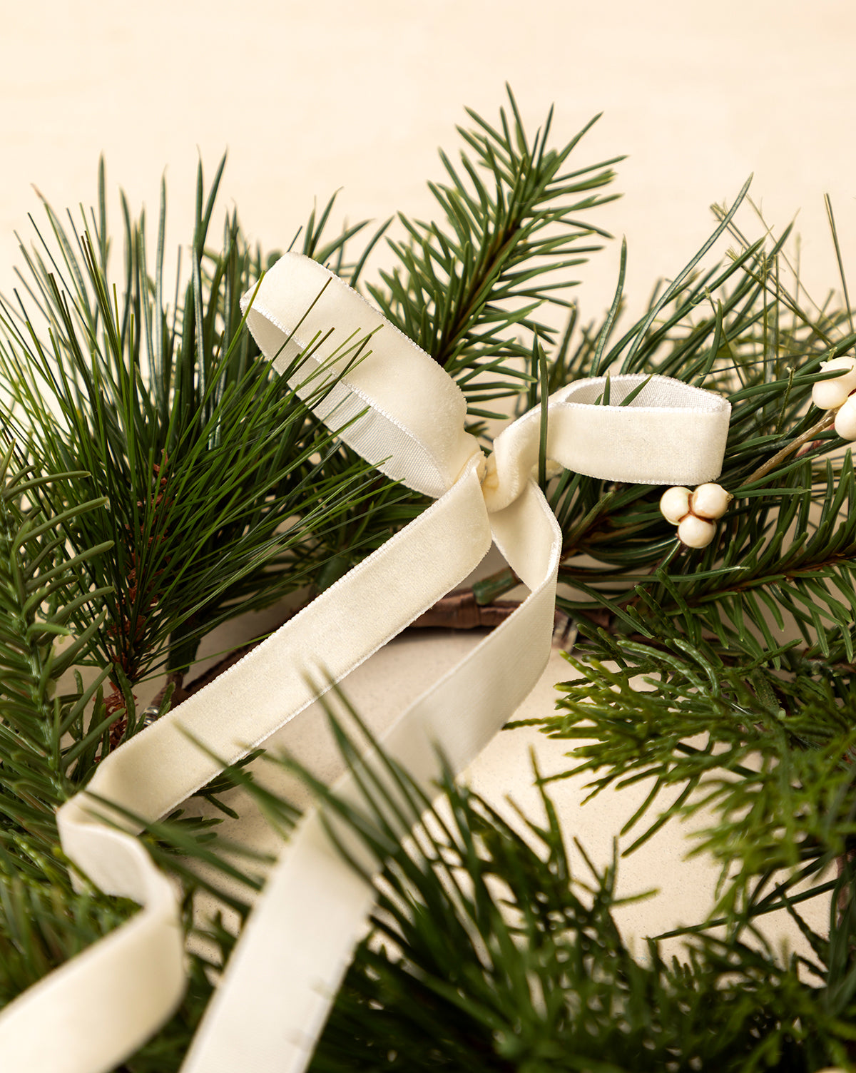 A close-up of the 8" Pine Needle & Berry Faux Wreath, featuring lush green pine branches, white berries, and a cream satin ribbon—an elegant festive accent for your holiday home decor, by Vendixs