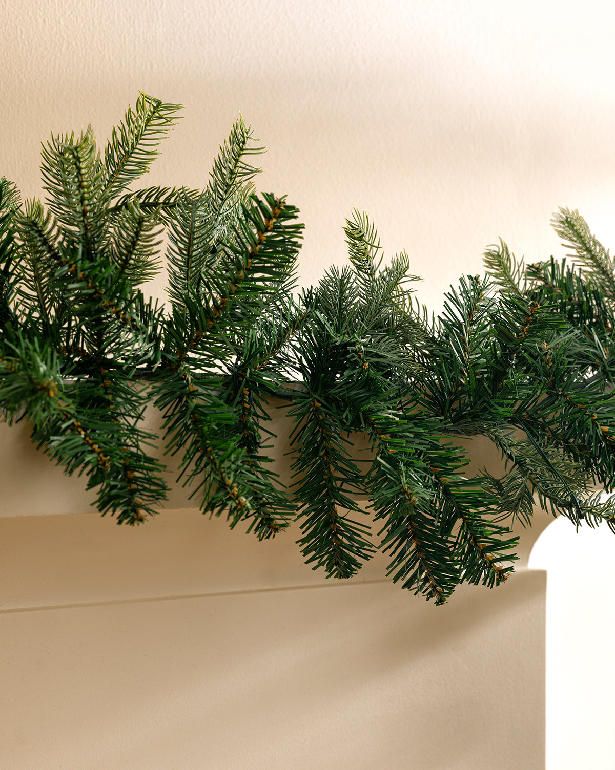 The 9' Grandis Pre-Lit Garland Indoor/Outdoor Faux Garland drapes beautifully along a white mantel, with lifelike green pine needles contrasting a neutral wall—ideal for classic holiday décor, by Vendixs