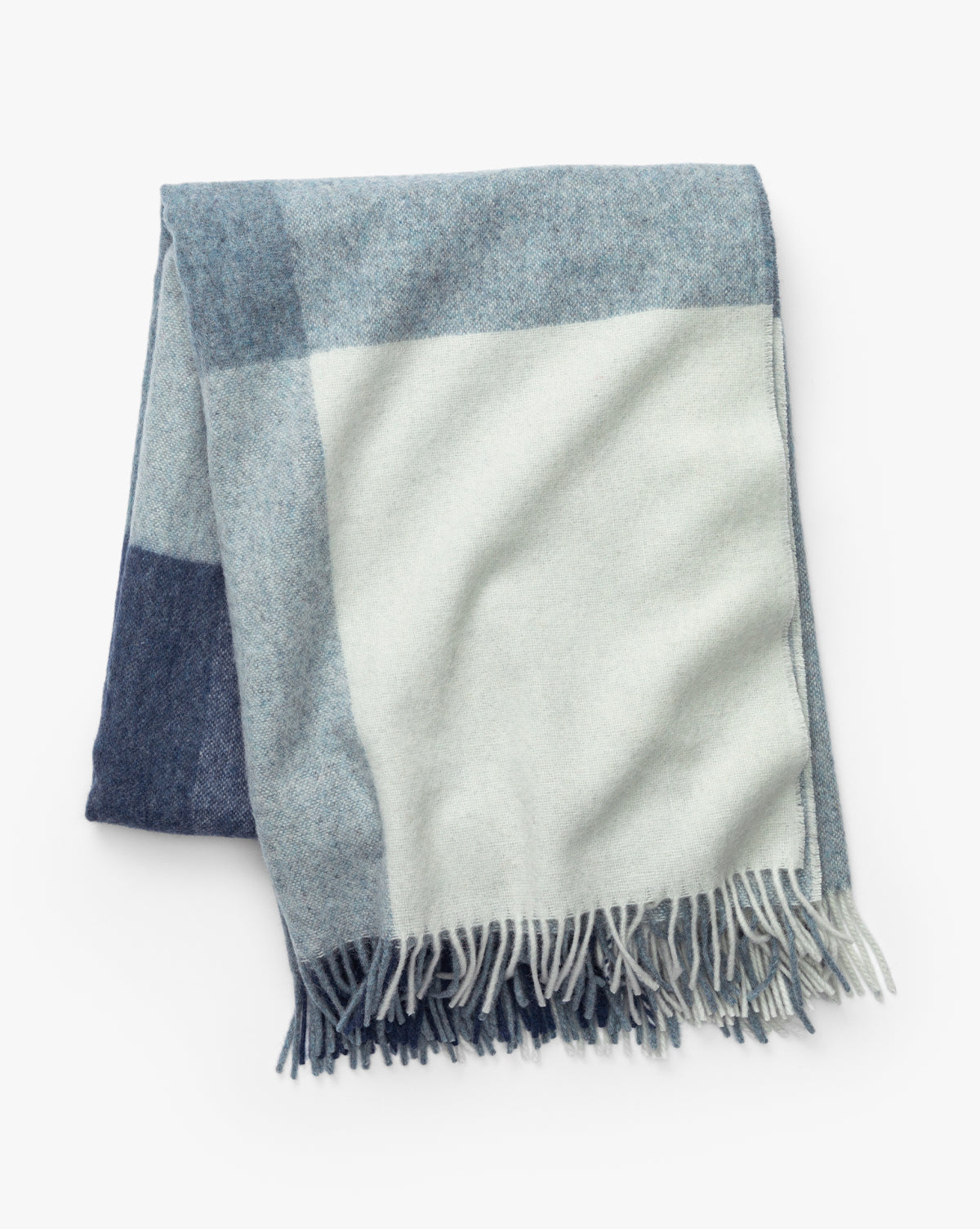 The Abner Throw by Fibre is an eco-friendly blanket made from recycled alpaca wool, featuring large light blue, gray, and cream checkered blocks with fringed edges by Vendixs