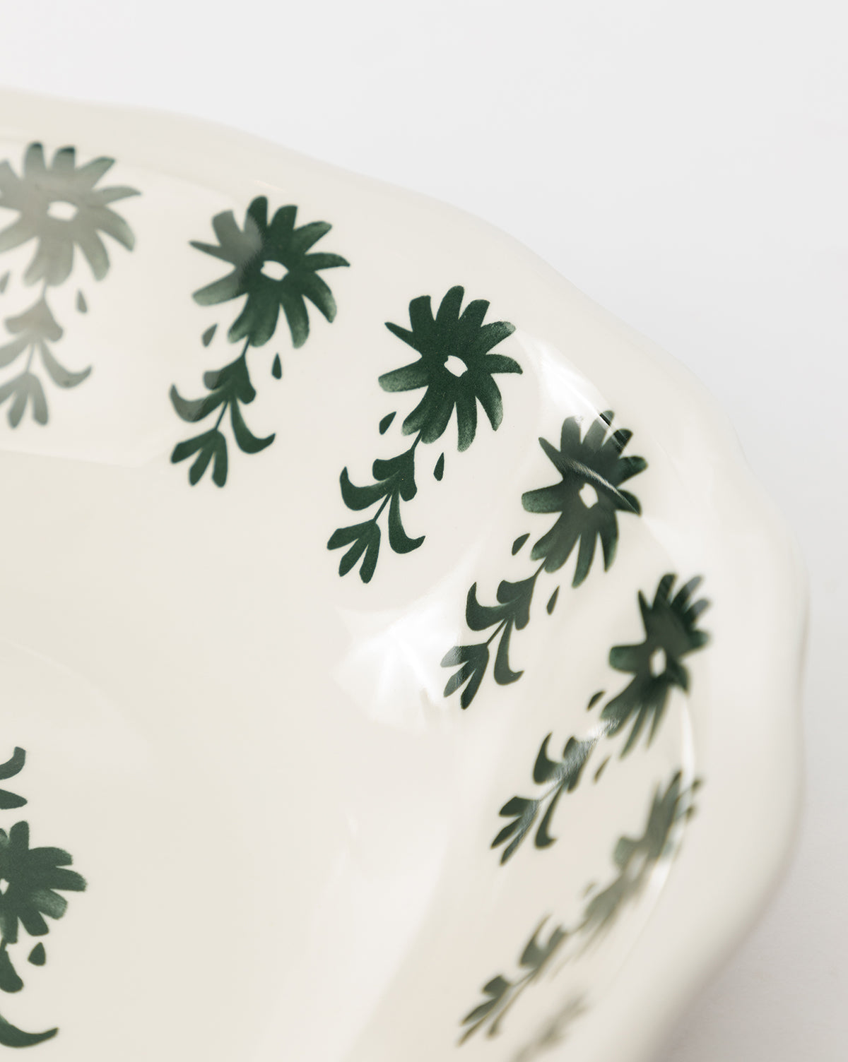 A close-up of the Alba Melamine Serving Bowl, featuring a white finish, scalloped edge, and a dark green floral motif along the rim, by Vendixs