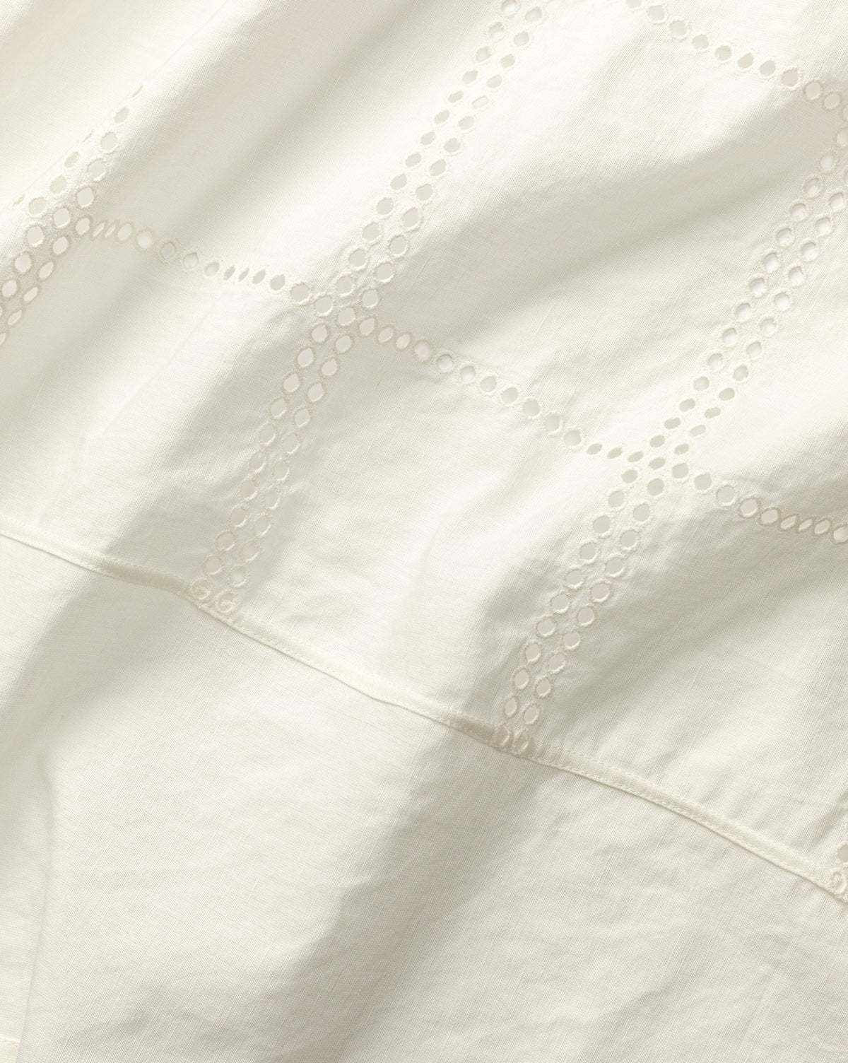 Close-up of Albany Shower Curtain’s white linen-cotton fabric with small circular cutouts forming grid lines, giving a soft, textured look—ideal for adding elegance to your bathroom decor, by Vendixs