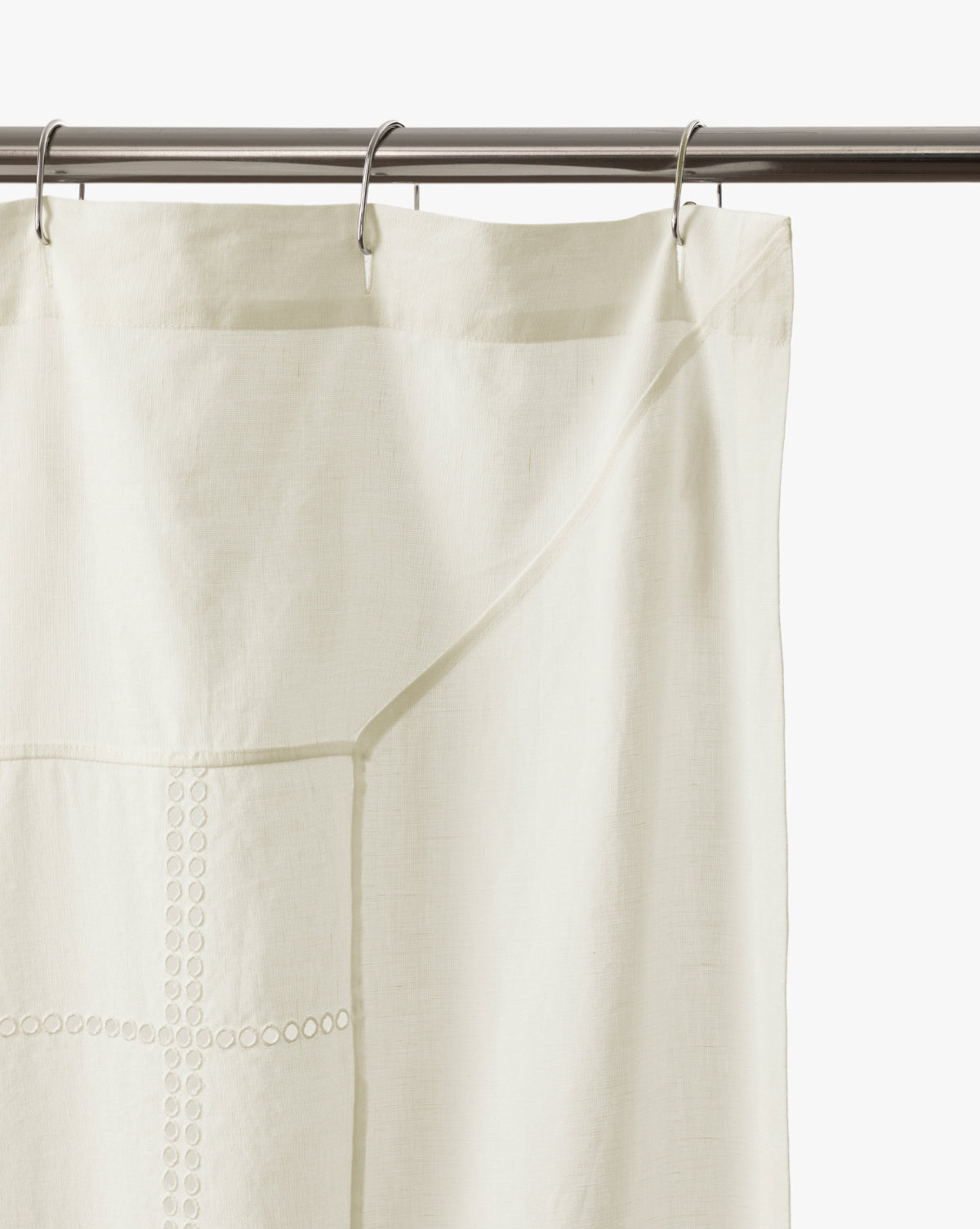 The Albany Shower Curtain in off-white linen-cotton hangs from a silver rod with metal rings, featuring subtle top embroidery—an elegant addition to your bathroom decor, by Vendixs
