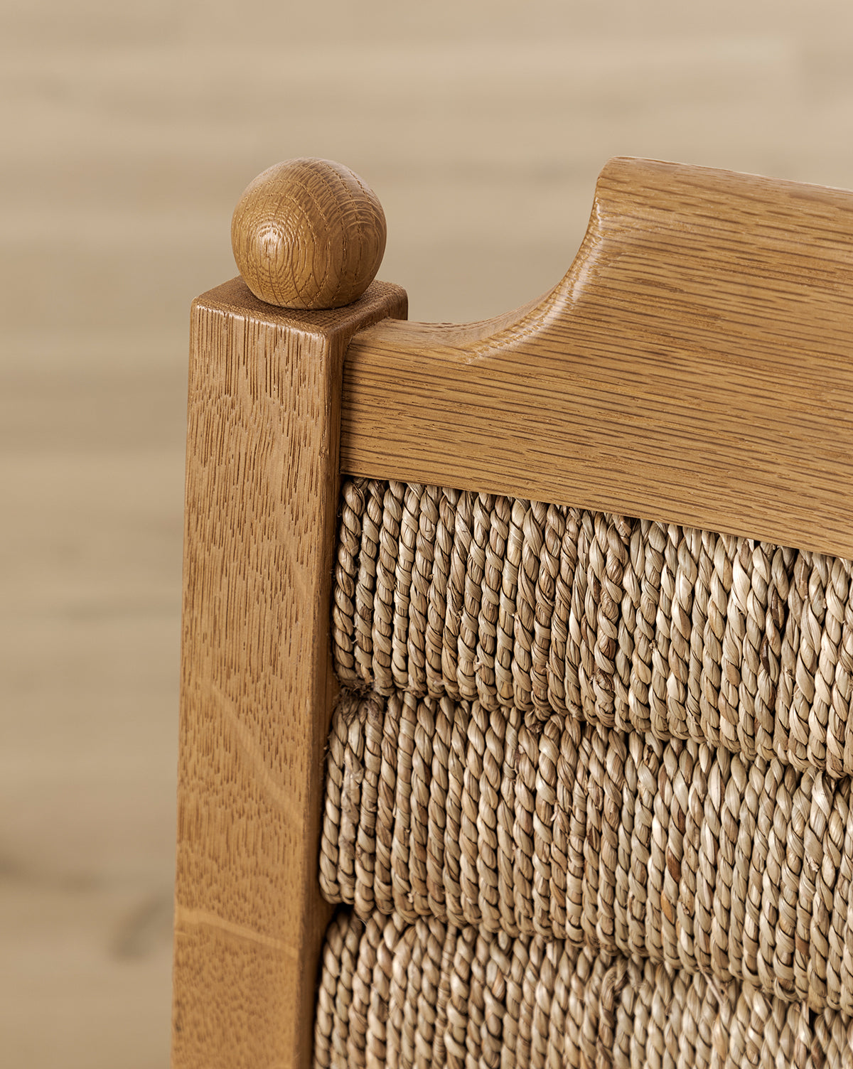 Certainly! Here’s your revised description with the exact string “McGee & Co.” blended seamlessly at the end: Close-up of the honey oak Makerspalm Alberta Counter Stool’s top corner, showing a rounded finial and woven rattan backrest against a blurred, light background. Vendixs