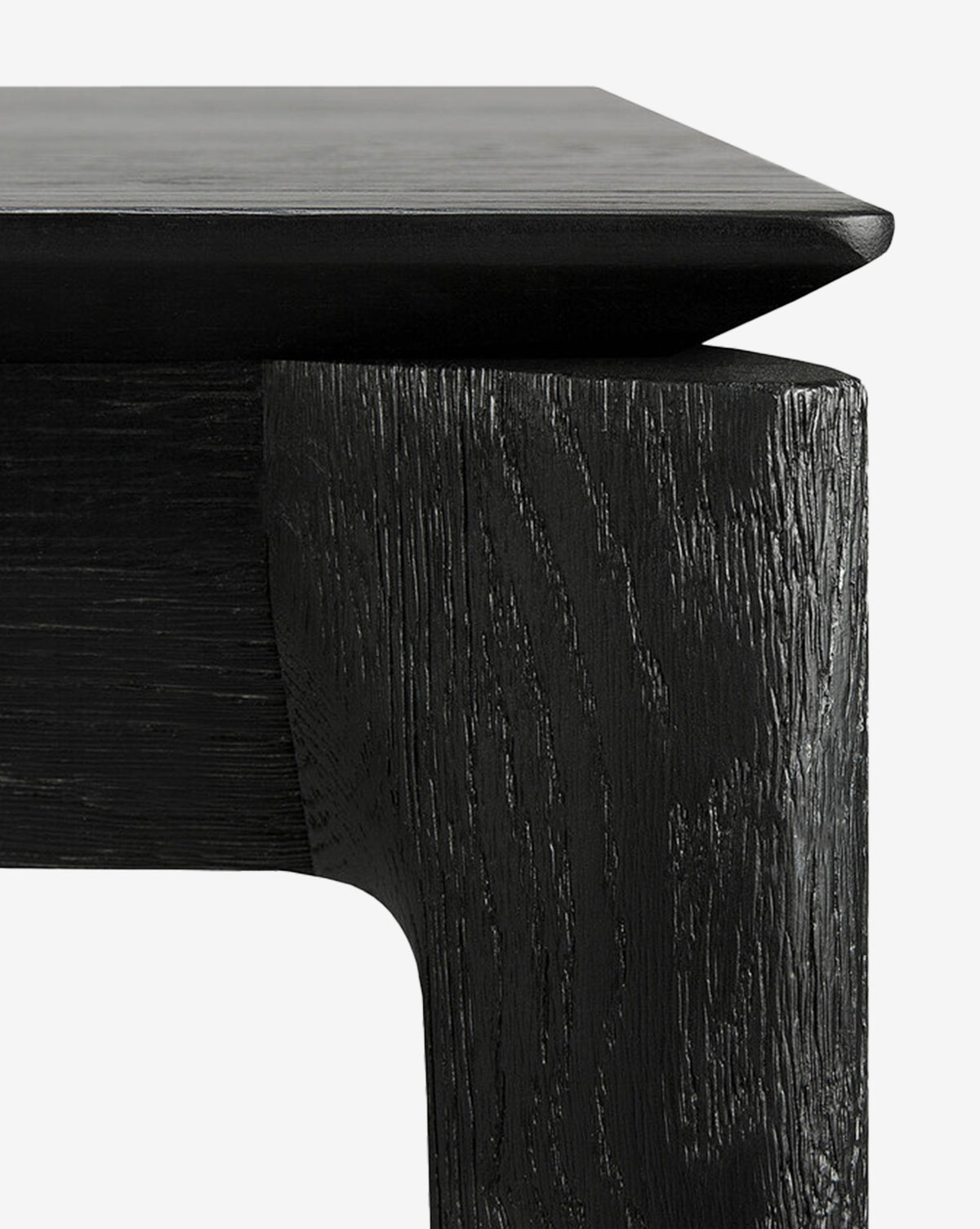 Close-up of the Alec Dining Table’s black wooden corner highlights its textured grain and sturdy build, making it a stylish addition to any dining room, by McGee & Co.