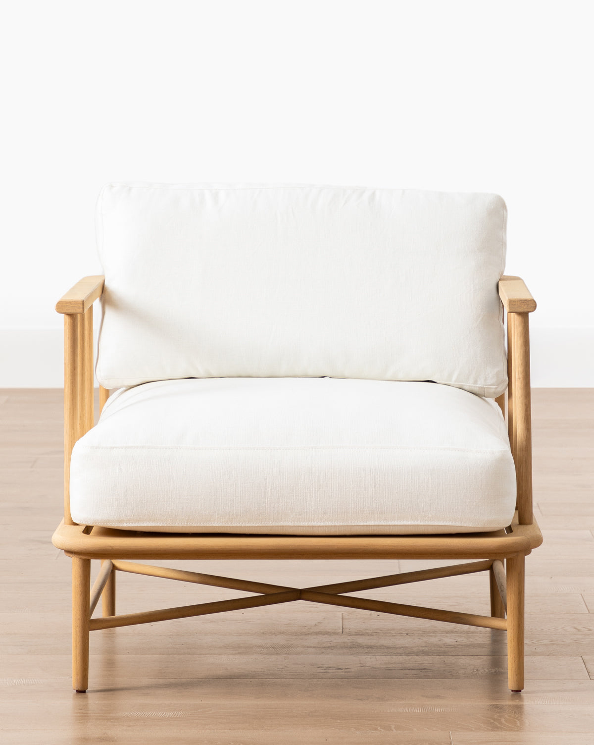 The Alma Lounge Chair features a light solid oak frame with white cushioned seat and backrest, set on a light wood floor against a plain white background—a stylish contemporary accent for any space by Vendixs