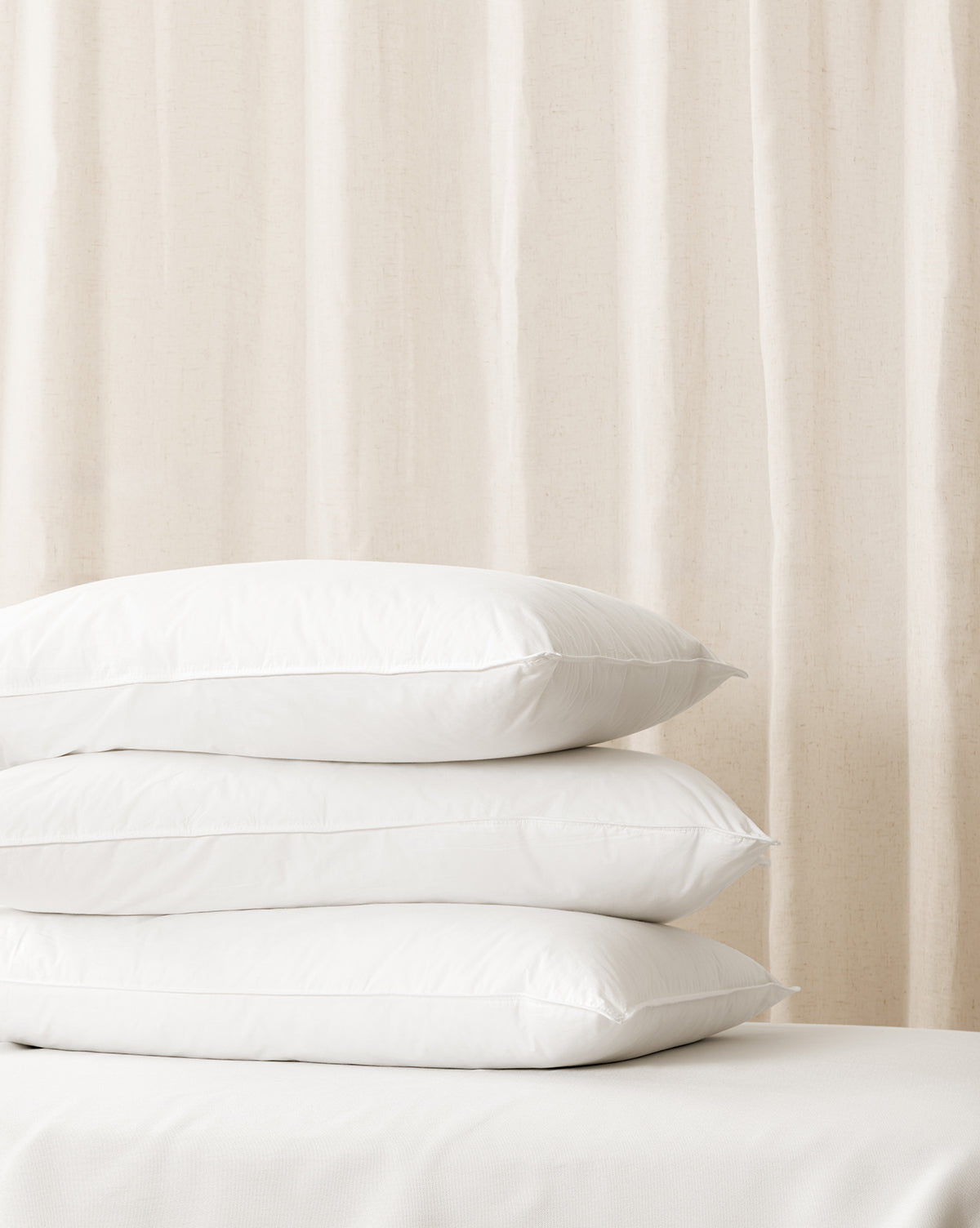 A stack of white, plush pillows with a soft focus background from Vendixs