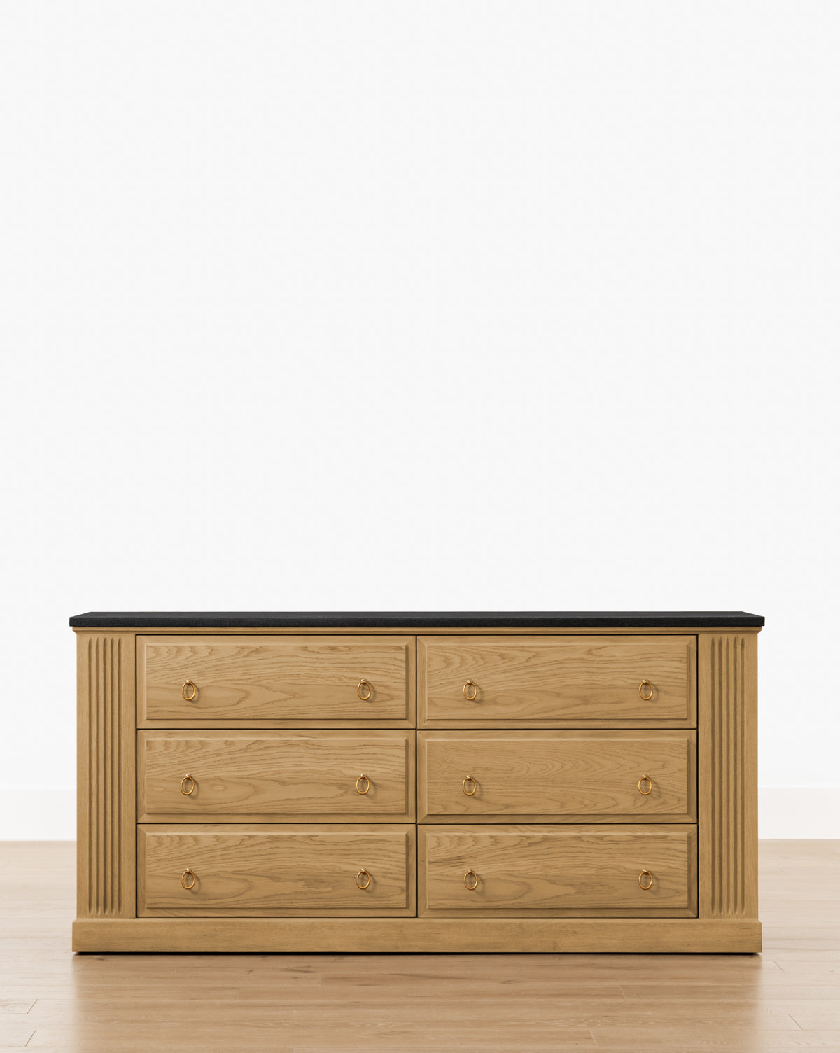 An Ambrose Dresser by YANG CHENG WOODEN INDUSTRIES INTERNATIONAL (VIETNAM) CO LTD features six drawers, solid brass drop pulls, vertical fluted side accents, and a dark flat top, shown on a light wood floor against a white background. Vendixs
