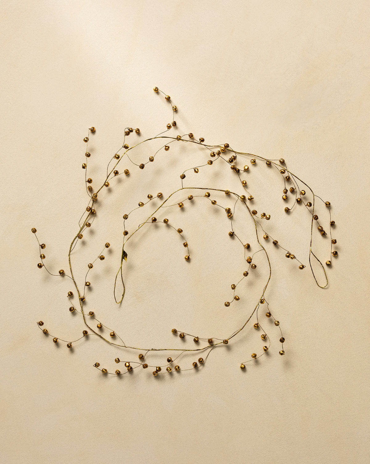 The 6' Angelica Gold Garland features delicate gold beads on thin wire, arranged in loose circles on a light beige background to add an elegant touch to your holiday decor, by Vendixs