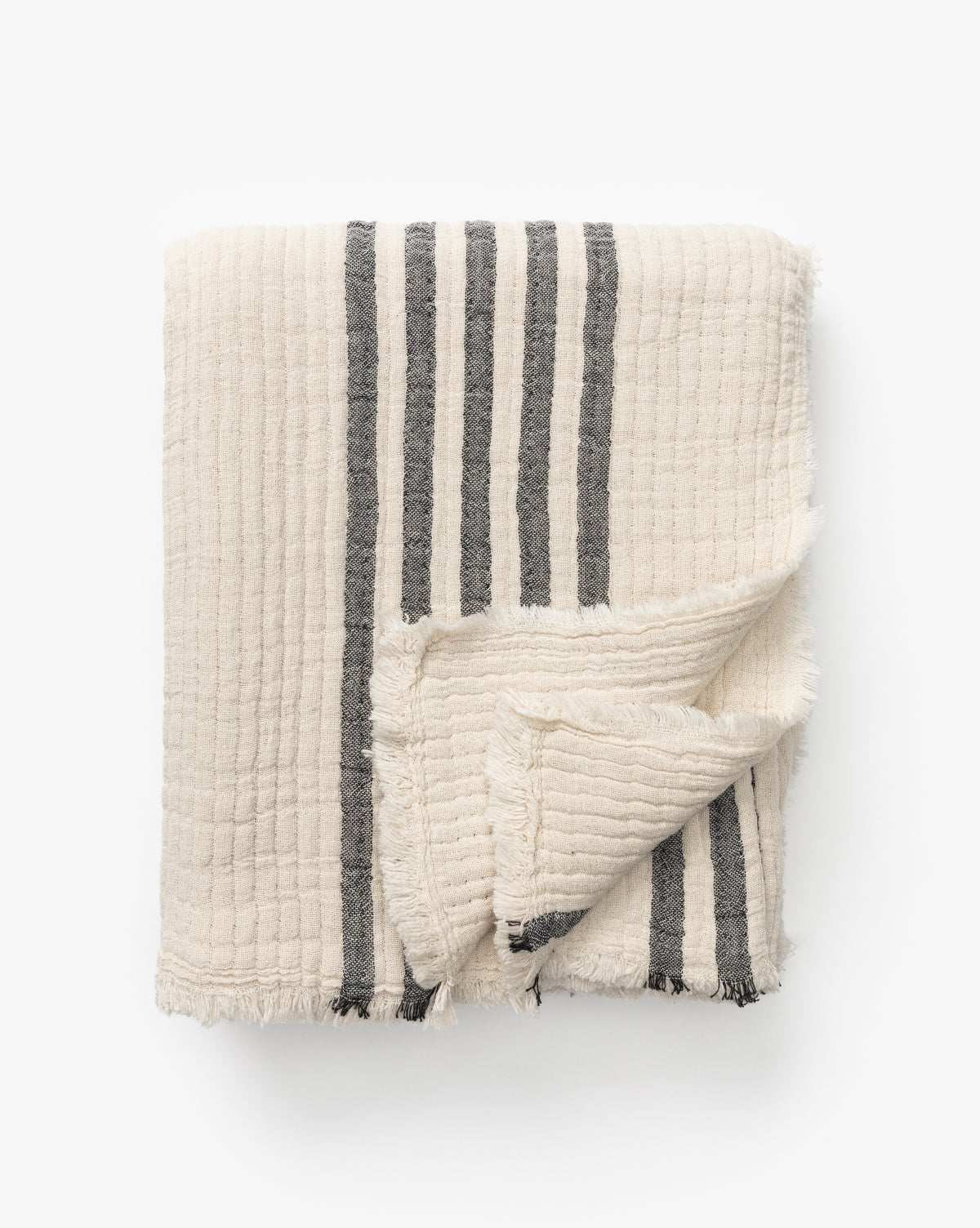 The Anneliese Striped Throw by Creative Co-op features cream cotton with a grid texture, dark gray vertical stripes, and fringed edges—an elegant piece for luxury home decor, shown on a white background by Vendixs