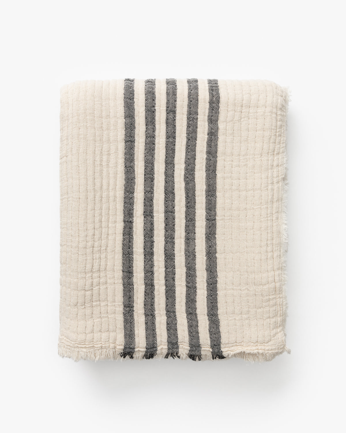 The Anneliese Striped Throw by Creative Co-op features cream-colored cotton with four vertical dark gray stripes and slightly frayed edges, shown folded on a white background for a luxe home decor accent by Vendixs