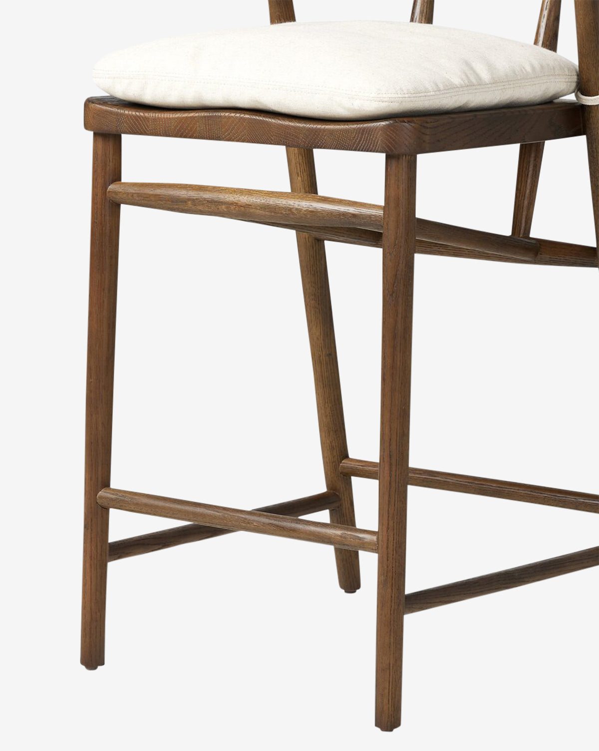 A close-up of the Four Hands Ardent Stool shows its solid oak frame and light cushioned seat, highlighting the legs, seat, and backrest—an ideal addition to any kitchen bar set against a plain background. Vendixs