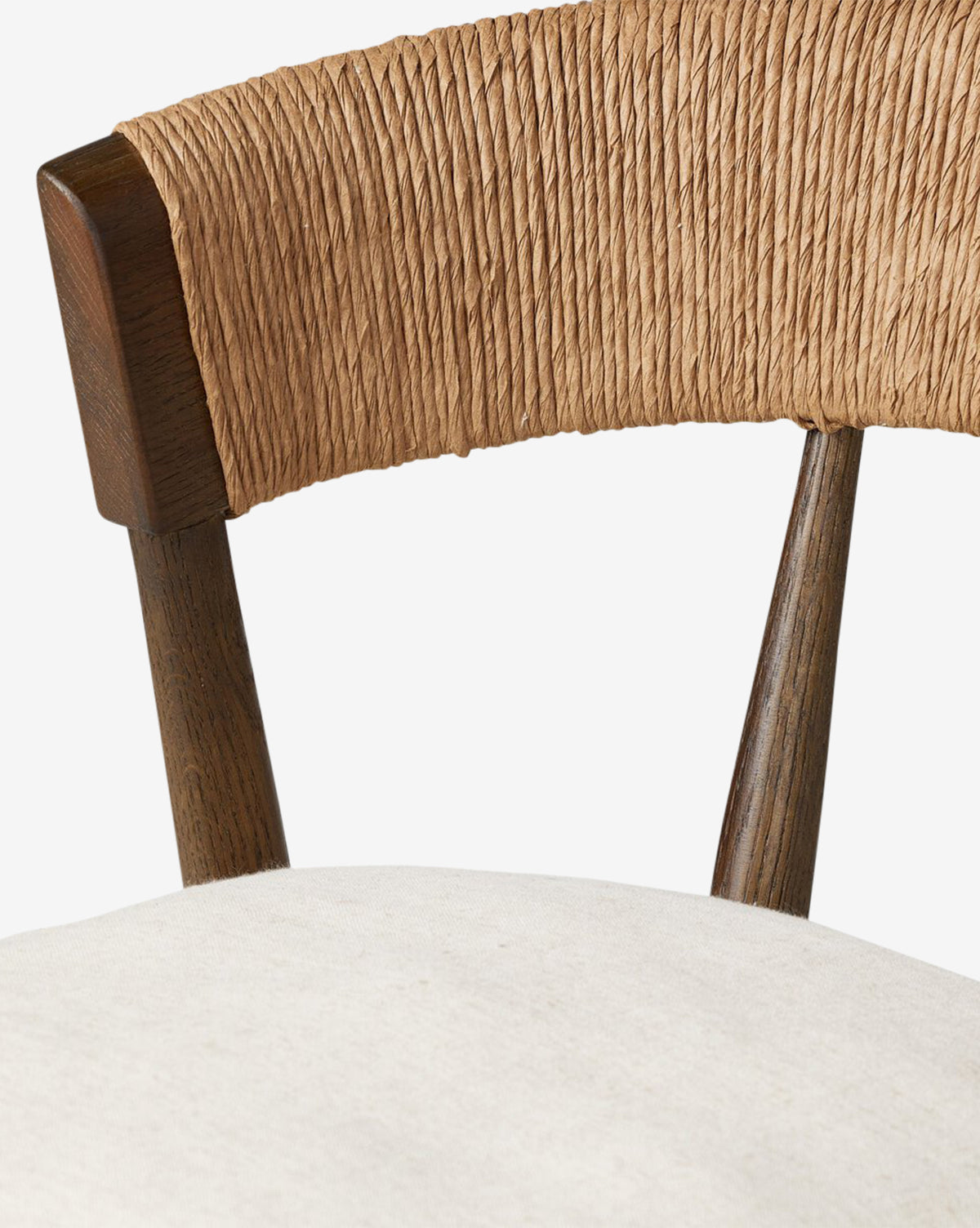 Close-up of the Four Hands Ardent Stool, showcasing a solid oak frame with a curved woven backrest and off-white cushioned seat. The dark wood finish adds elegance—ideal for a kitchen bar. Plain white background. Vendixs