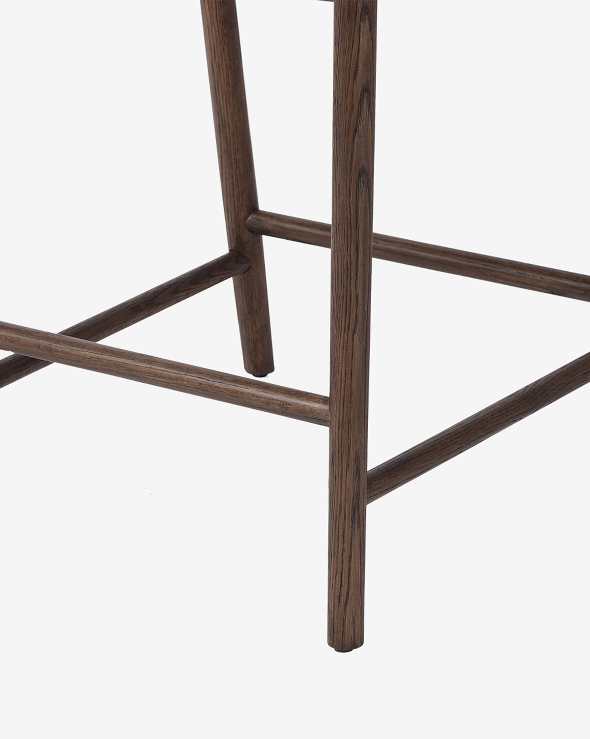Close-up of the Ardent Stool by Four Hands, highlighting its oak frames wooden legs and crossbars with a dark wood finish and minimalist design, set against a plain white background. Vendixs