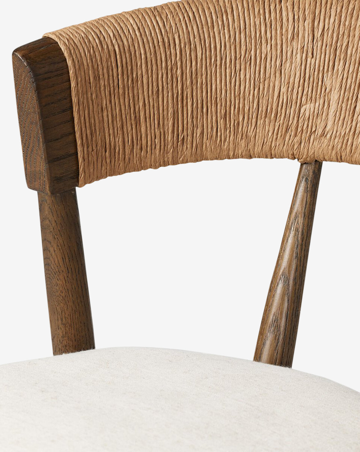 Close-up of the Ardent Stool by Four Hands, showcasing twisted natural paper rush wrapped around the curved backrest, dark wooden supports, and a light cushioned seat. Vendixs