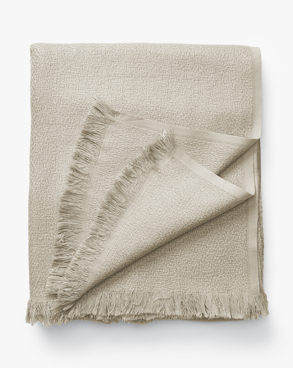 The Ariella Throw by J Call Designs LLC dba Sew Miami LLC is a light beige cotton throw with fringed edges and subtle texture, shown neatly folded on a white background—ideal for enhancing a neutral color scheme. Vendixs
