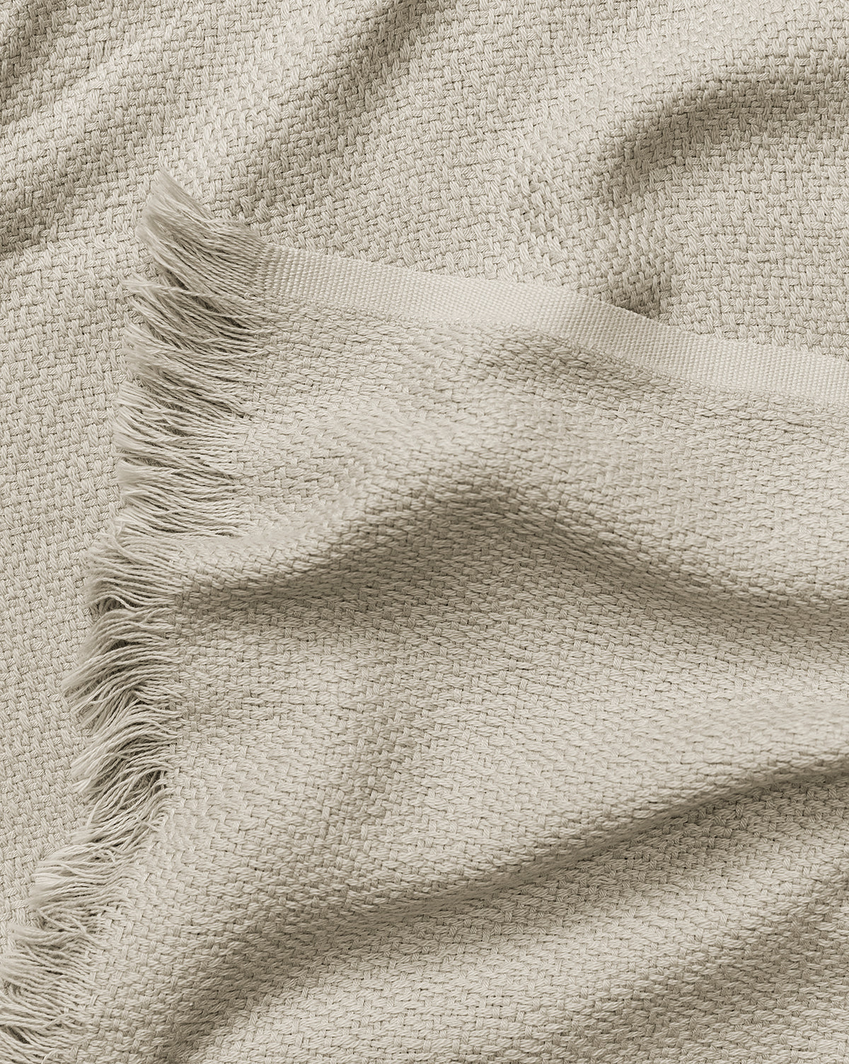 The Ariella Throw by J Call Designs LLC dba Sew Miami LLC features beige woven fabric with a textured pattern and fringed edge, appearing soft and cozy—the perfect neutral cotton blanket or stylish accent for your home. Vendixs