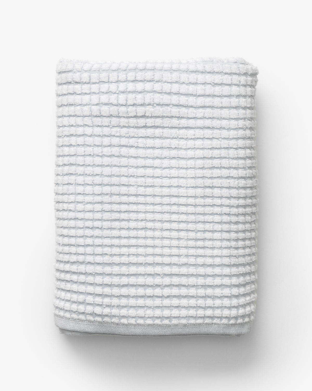 A neatly folded waffle weave towel in gray with a subtle grid pattern, placed on a plain background—an elegant addition to the Atrani Gray Organic Bath Collection, by Vendixs