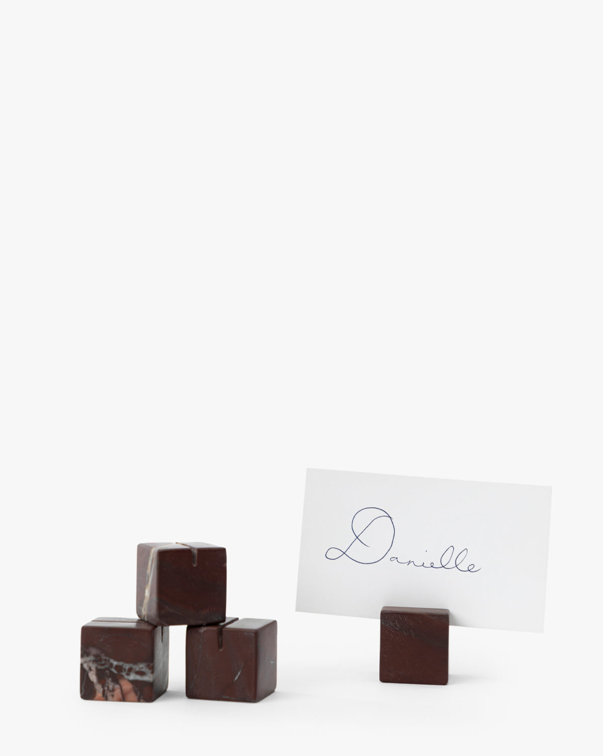 Four dark Auburn Marble Place Card Holders are stacked on the left, with one holding a white Danielle card on the right. These elegant holders are perfect for harvest tablescapes or holiday gatherings. Set of 4, by Vendixs