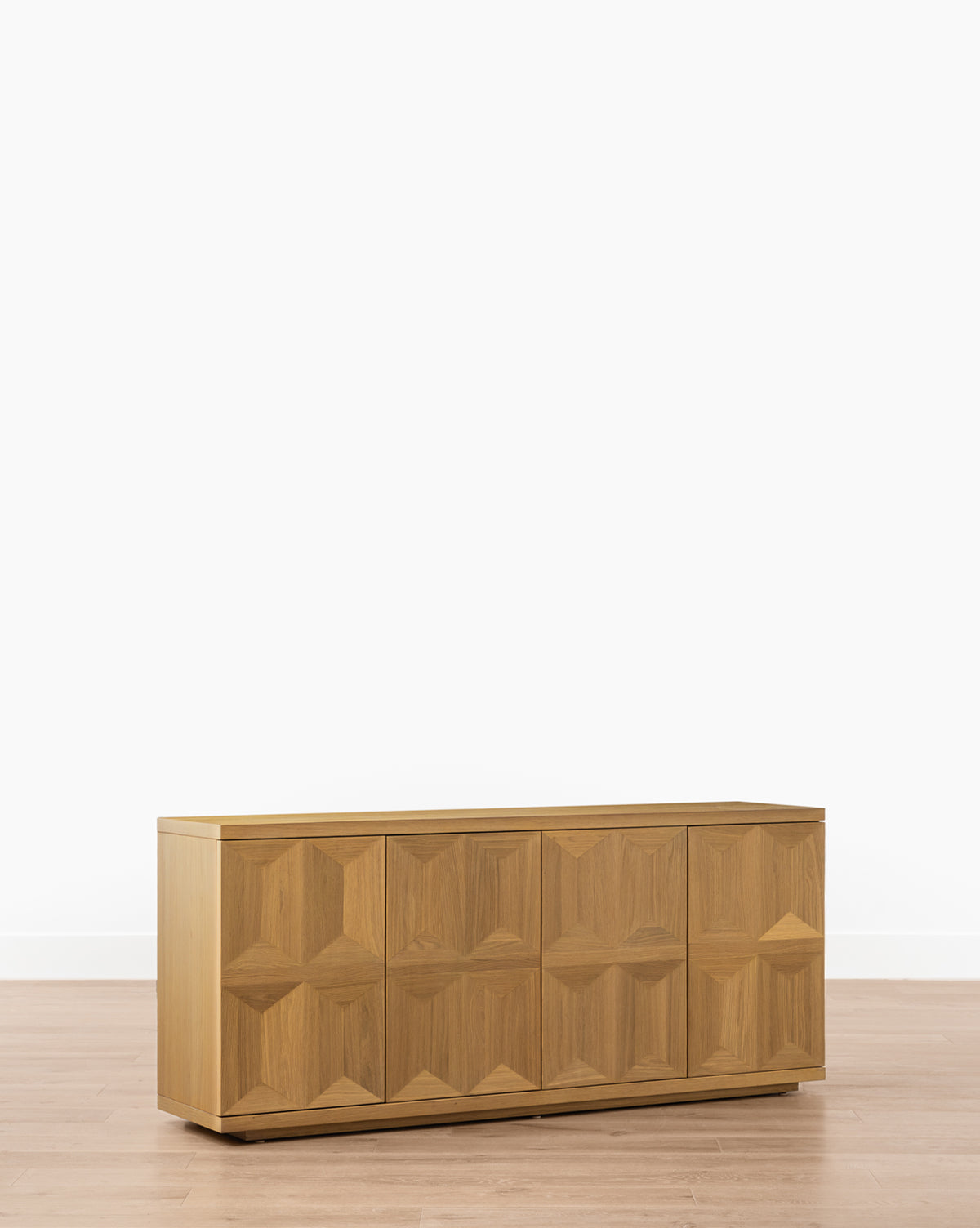 The Beacon Sideboard features four doors with a geometric raised pattern, spacious storage, and a neutral finish that looks stunning on light wood floors and against plain white walls, by McGee & Co.