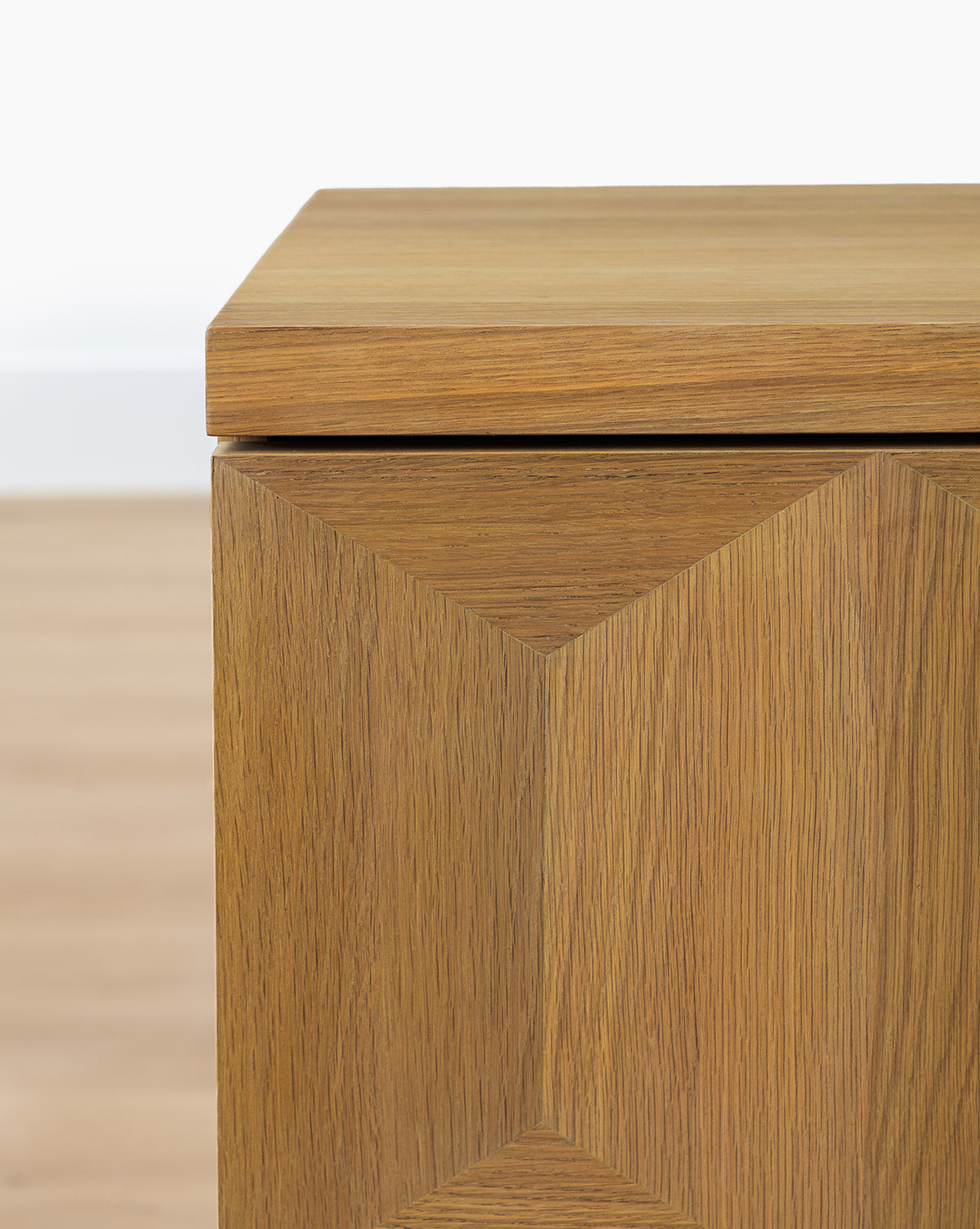 The Beacon Sideboard features a geometric diamond pattern on its doors and a neutral finish, providing ample storage, by Vendixs Shown here with a light wood floor and white wall backdrop.