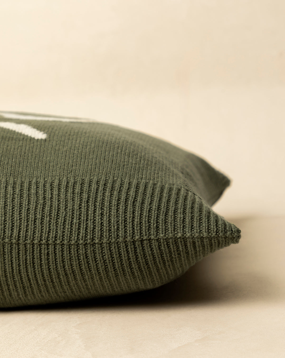 Close-up of the green Bella Pillow Cover, featuring a knit texture and white stitching, displayed on a light surface against a neutral background—ideal for holiday layering, by McGee & Co.