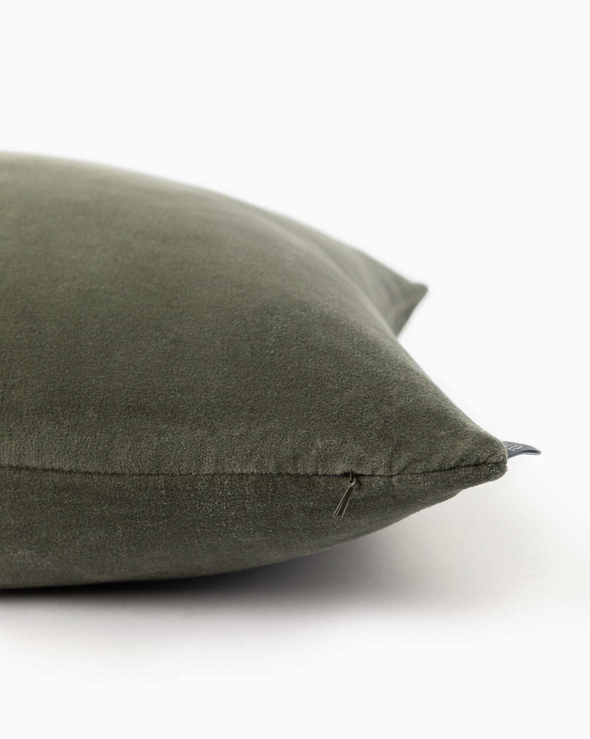A close-up of the Bellevue Velvet Pillow Cover in green stone washed velvet, featuring a visible zipper on one edge, set against a white background, by Vendixs