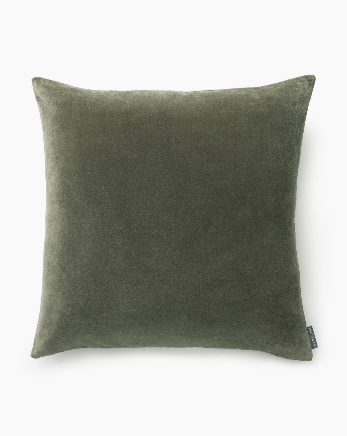 The Bellevue Velvet Pillow Cover is a square, olive green, stone-washed velvet cover with a soft texture. Displayed against a white background, it features a small fabric tag on one side, by Vendixs