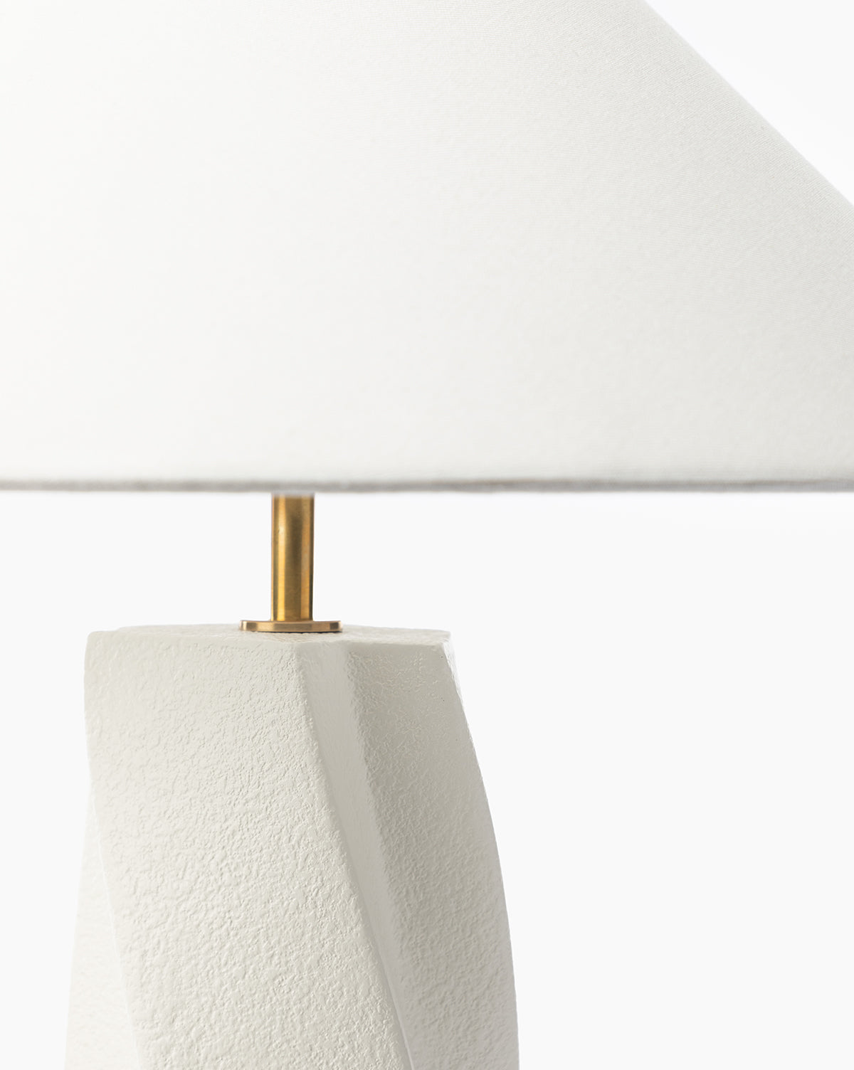 A close-up of the Bettencourt Table Lamp shows its textured white resin base, gold stem, and large linen shade set against a plain white background, by McGee & Co.