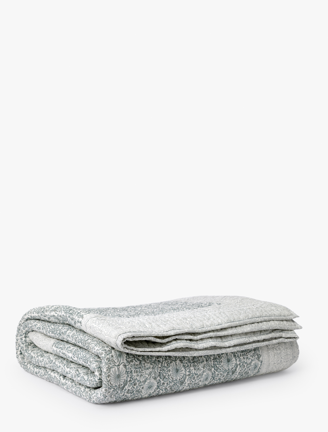 The Blue Floral Block Print Quilt, featuring a neatly folded design and subtle floral motifs, is displayed on a white background—perfect for bringing artisanal charm to your bedding, by Vendixs