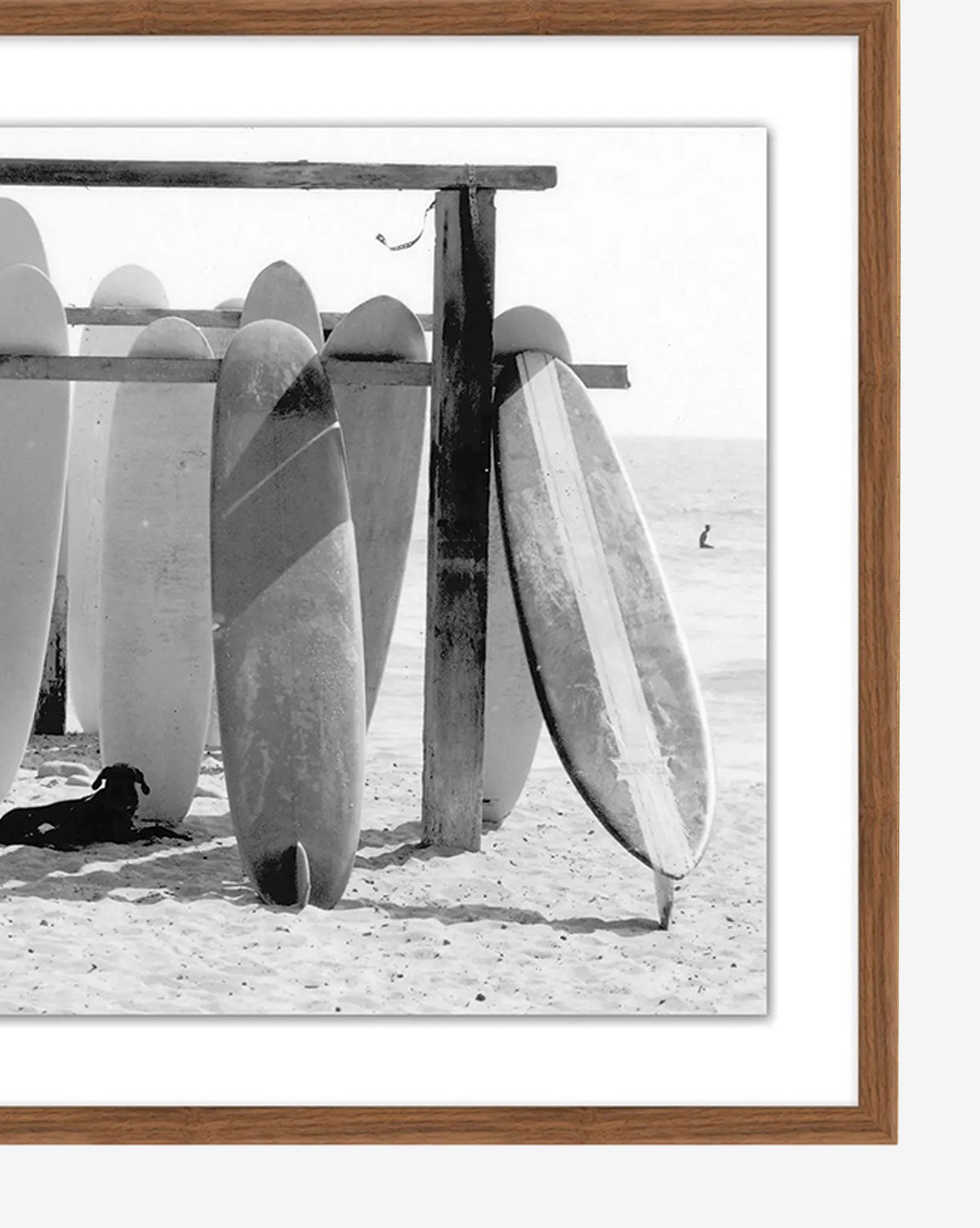 Boards at the Ready—a black and white photo of surfboards upright in sand beneath a rack, with a dog resting in the shade and ocean view—captures classic surf culture. Makes an ideal giclée print for any beach lover, by Vendixs