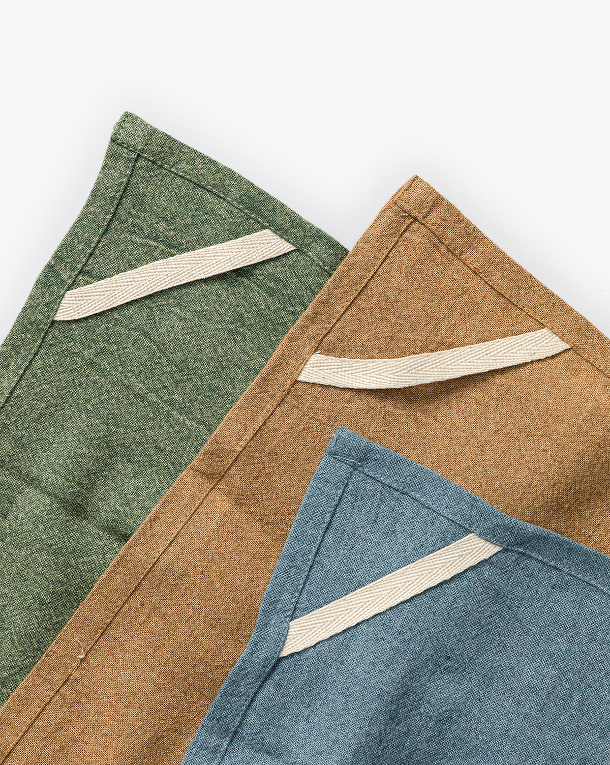 The Bradford Linen Blend Tea Towels (Set of 3) in green, brown, and blue overlap on a white background. Each towel has a beige fabric loop sewn near the corner for easy hanging, by Vendixs