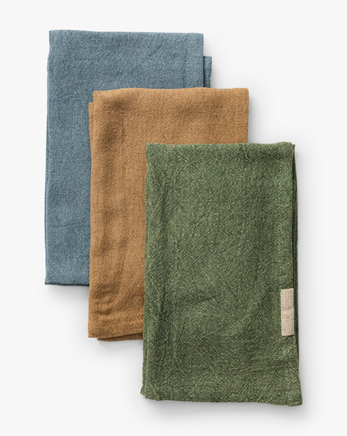 The Bradford Linen Blend Tea Towels (Set of 3) are neatly folded in blue, brown, and green with a small white tag on the green towel—artisanally designed and stacked against a white background, perfect for any kitchen, by Vendixs