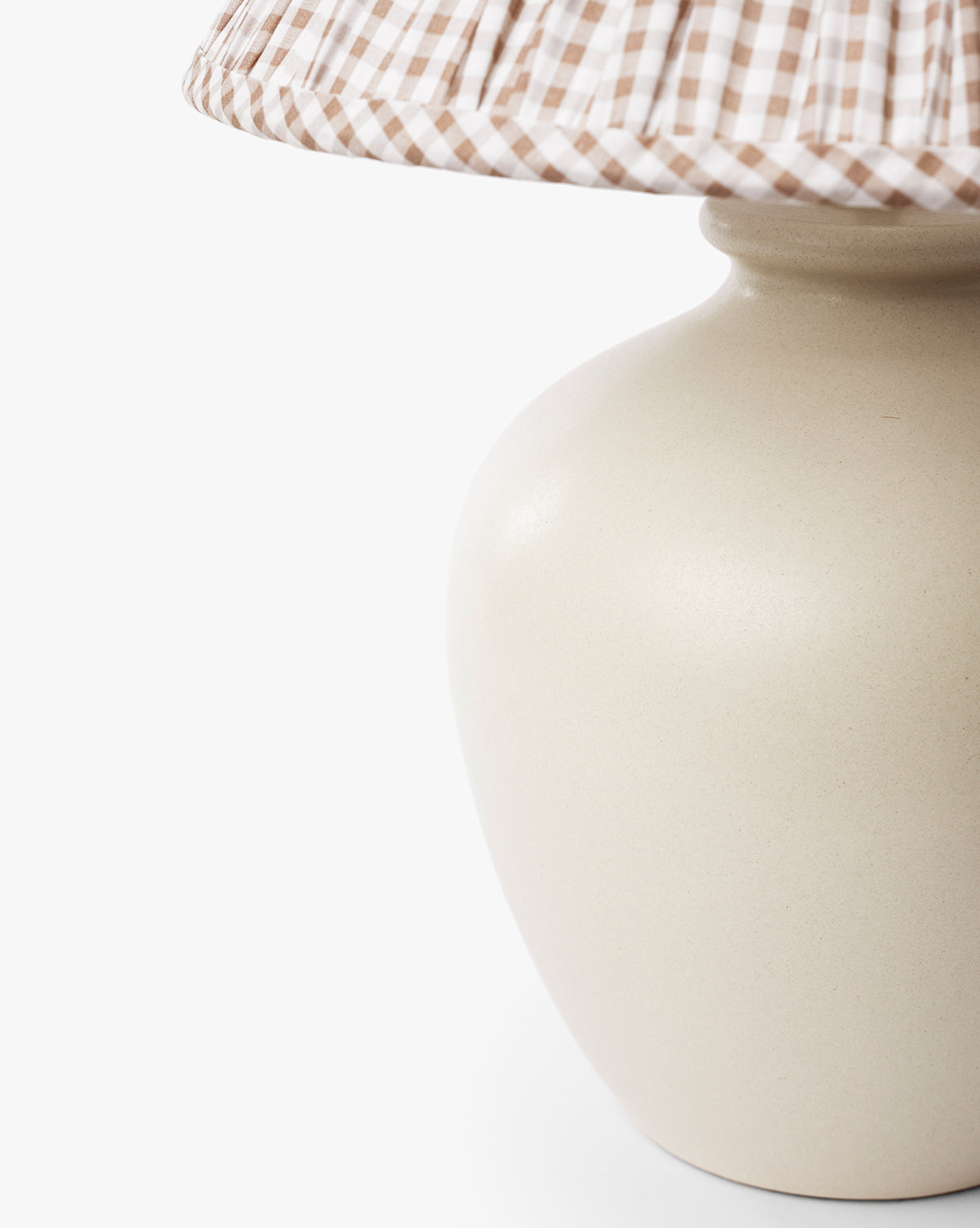 Close-up of the Bronwyn Table Lamp featuring a beige ceramic base and a brown-and-white gingham pleated shade, set against a plain white background, by Vendixs
