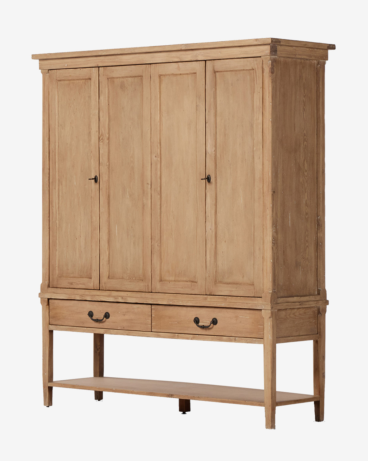 The Bryn Cabinet is a large solid pine armoire with four paneled doors, two drawers featuring distressed copper hardware, and an open bottom shelf in a light natural wood finish, by McGee & Co.