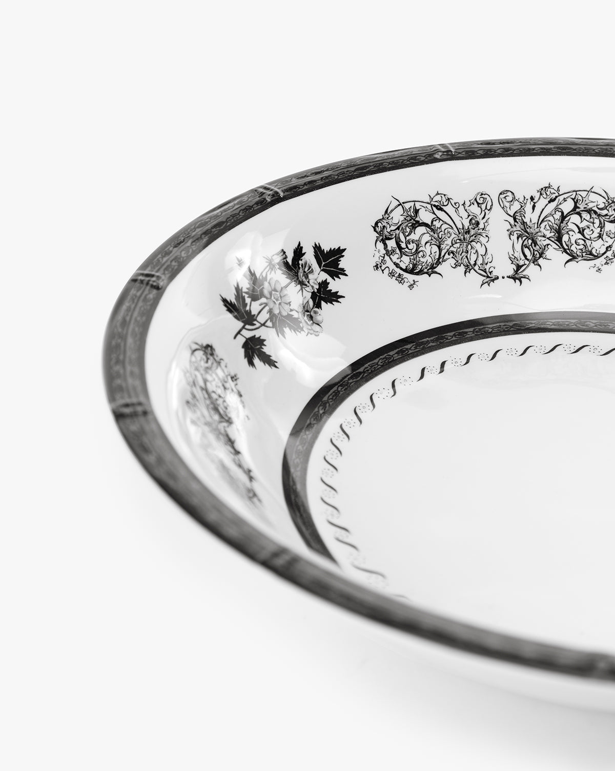 A close-up of the Calanthe Melamine Serving Bowl, featuring intricate black floral and scroll patterns on a decorative white rim, is photographed against a plain white background, by Vendixs