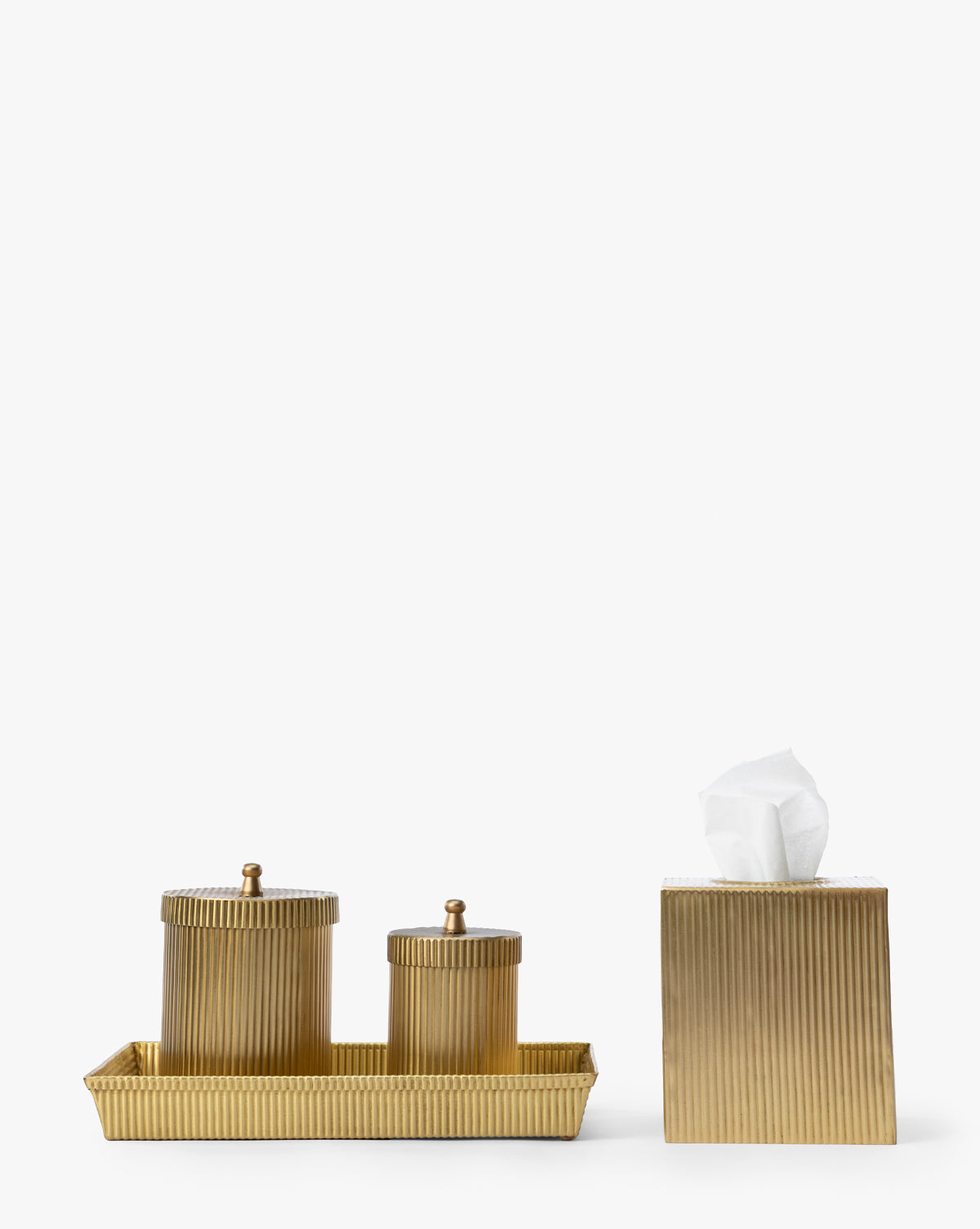 The Calvert Brass Tissue Box Cover, with its ribbed texture and elegant gold-toned finish, is shown alongside two lidded containers on a tray, all set against a white background, by Vendixs
