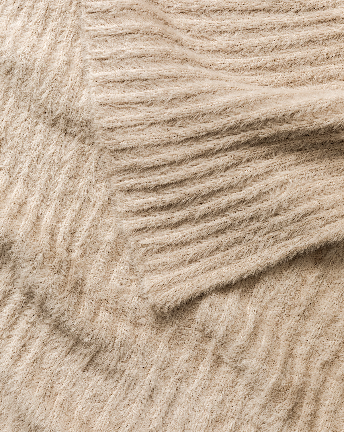 A close-up of the Caro Throw reveals its soft, beige ribbed knit with diagonal lines—perfect for bringing cozy, stylish home decor to any room, by Vendixs